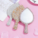 Close-up of sparkling crystals arranged in lip silhouette on handheld mirror