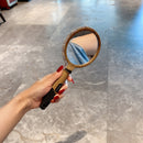 Hairbrush resting against mirror — lifestyle context on vanity table with soft lighting