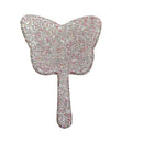 Champagne-pink teardrop mirror held in hand against soft natural lighting