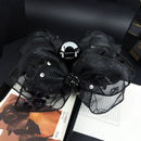 Front view of black rose-embellished shark clip hair accessory on white background