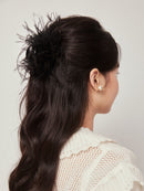 Black feather shark clip worn with loose wavy hair and linen top