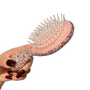 Three color variants of cushion hairbrush arranged together — white/black, pink/pink, yellow/green