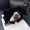 Black satin bow headband on white background, front view