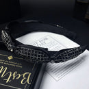 Side angle of wide black headband showing rhinestone placement and fabric texture