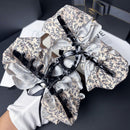 Black floral version of ribbon bow hair clip displayed on marble surface