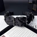 Side profile of satin headband highlighting smooth, stretchy band construction