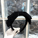 Black satin headband worn on model's head, side profile showing clean band contour